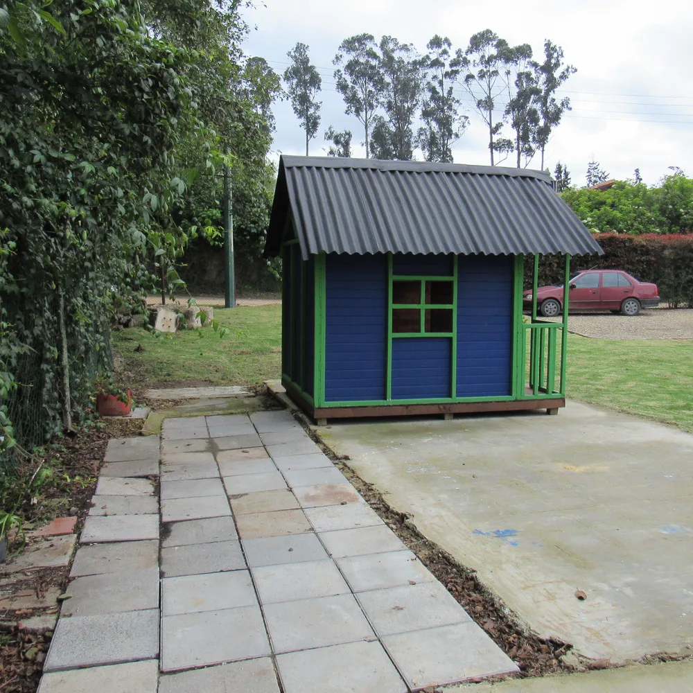 Casita de madera azul para jugar, junto al jardín