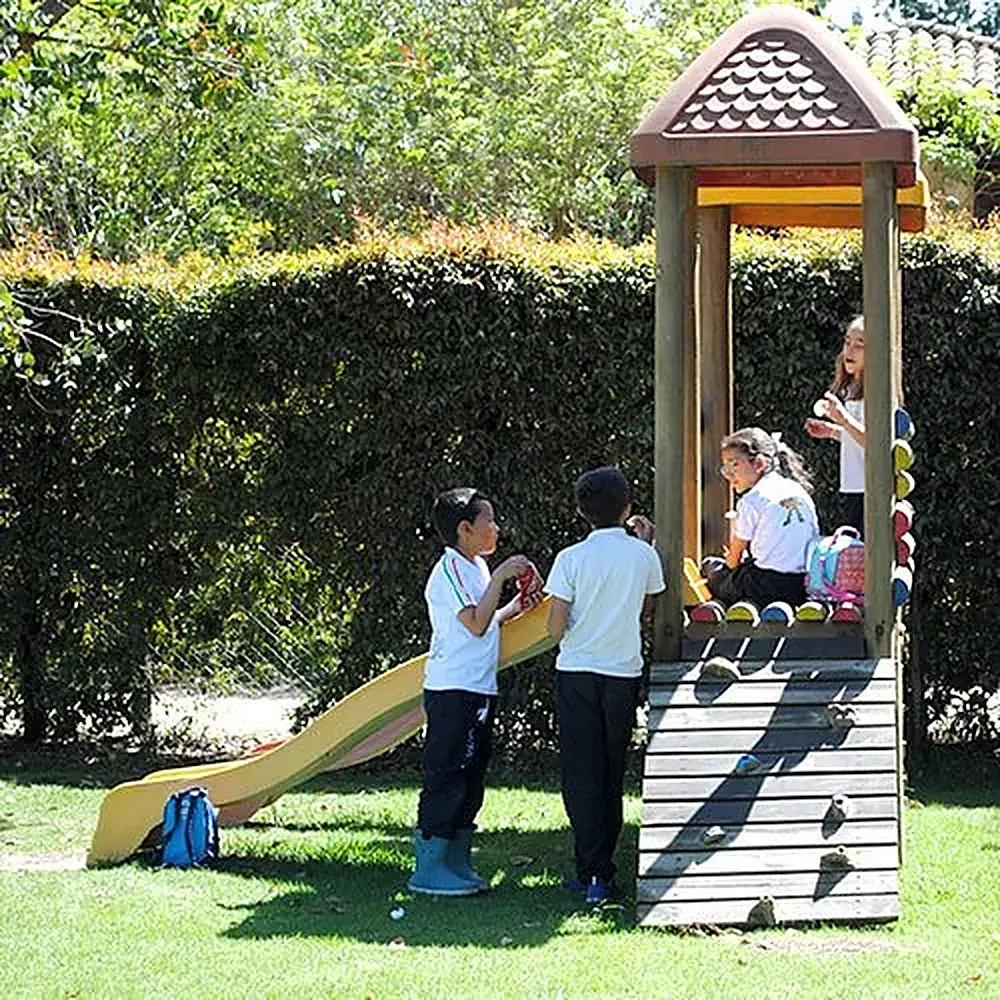 Niños de preescolar jugando en la torre de madera con tobogán