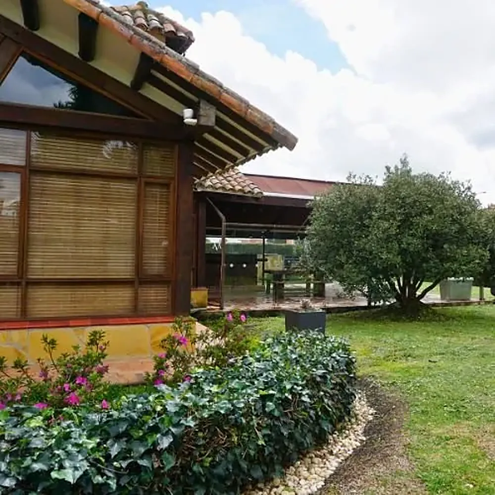 Casa principal de la sede Chía, con ventanales de madera y jardín