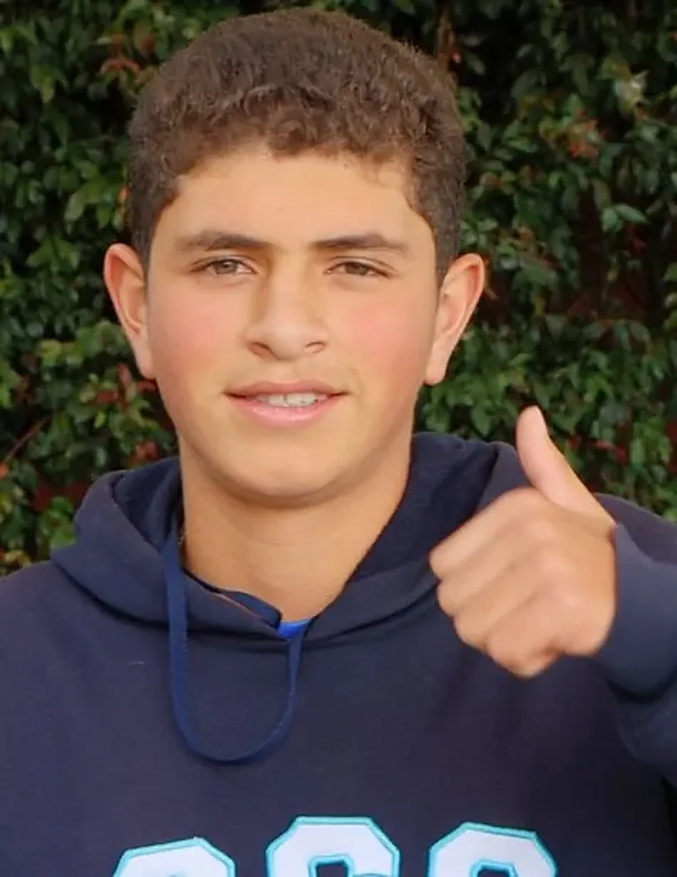 Estudiante de secundaria sonriendo con el pulgar arriba, con el buzo del colegio