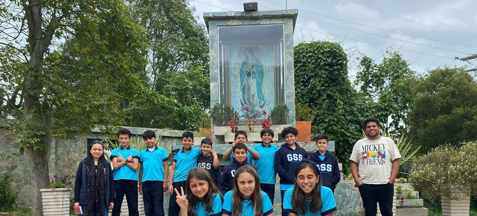 Estudiantes de secundaria con su profesora y un docente, junto al santuario de la Virgen de Guadalupe del colegio