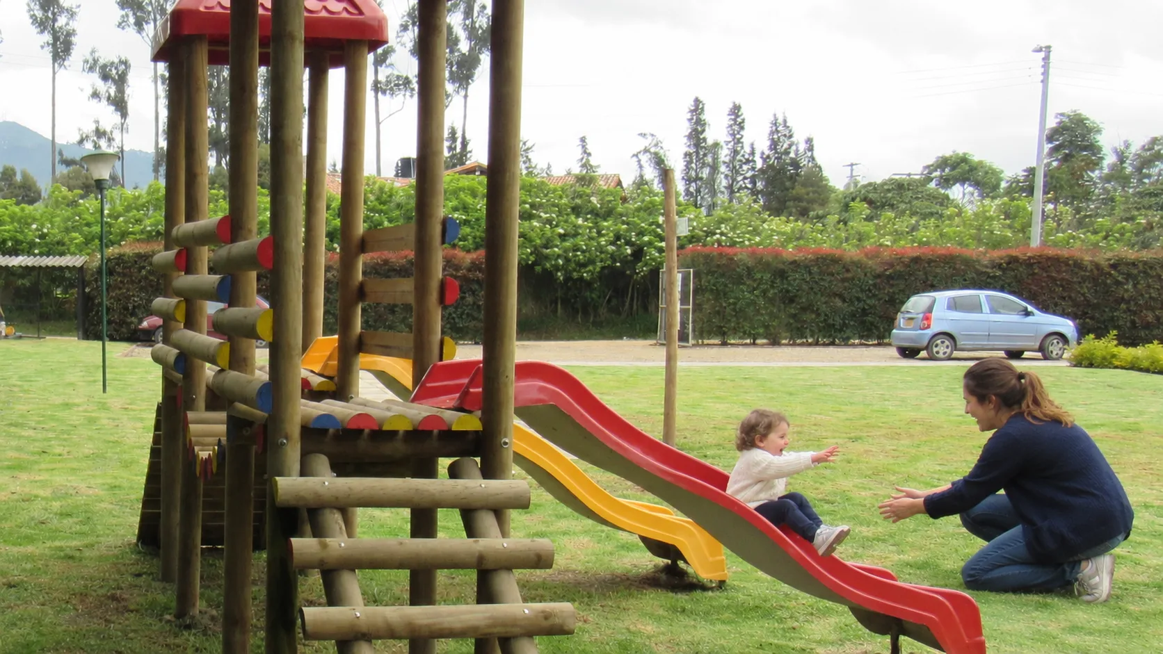Una profesora recibe a una niña de 2 años al final del rodadero, en el parque de la sede Cajicá