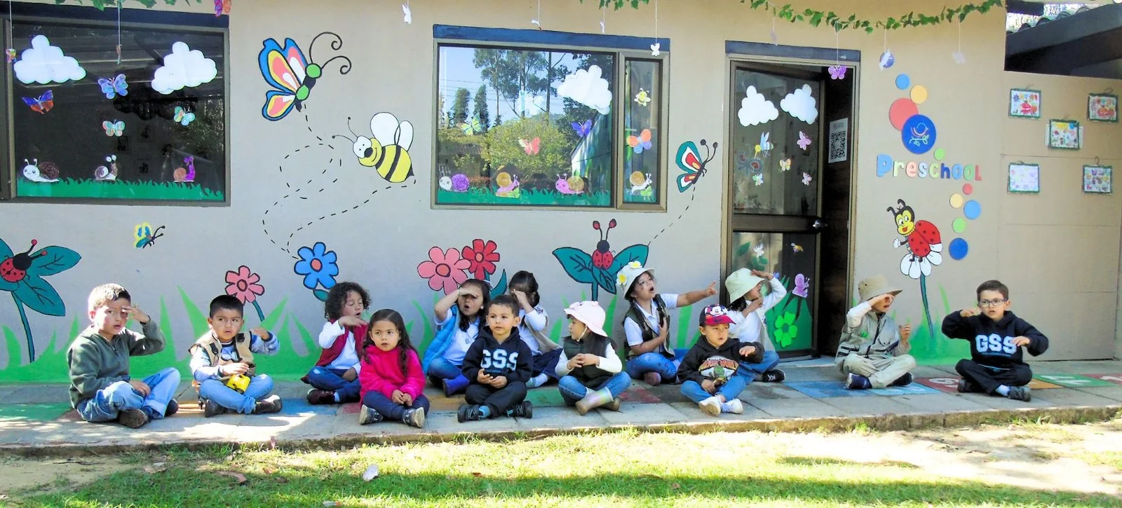 Niños de preescolar sentados en fila frente al mural de su salón, en la sede Cajicá